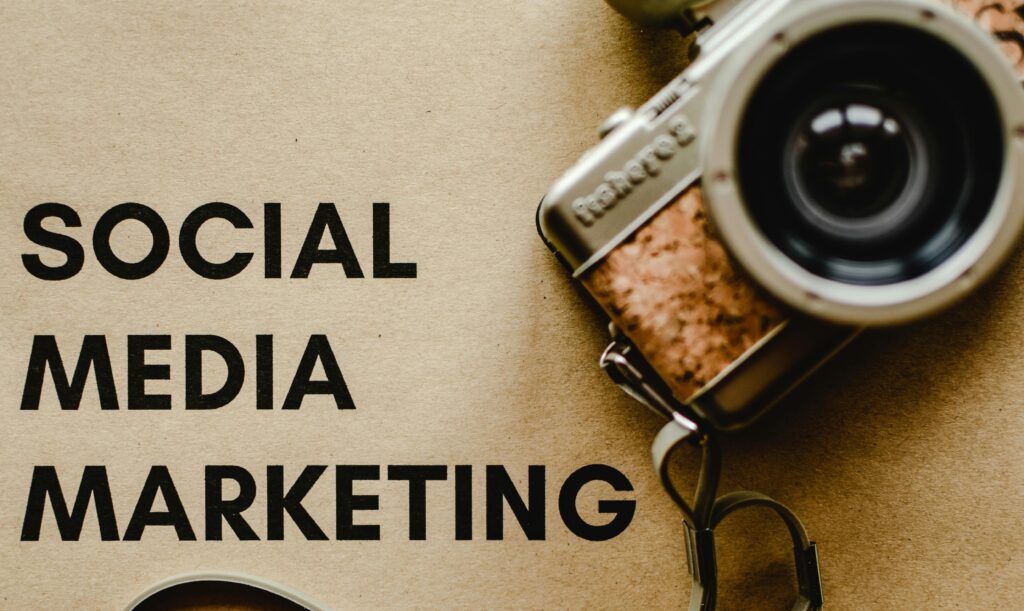 A vintage camera placed beside a paper with the words “Social Media Marketing,” symbolizing creativity and visual engagement while highlighting the benefits of social media marketing for businesses.