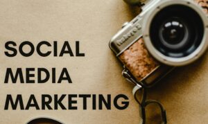 A vintage camera placed beside a paper with the words “Social Media Marketing,” symbolizing creativity and visual engagement while highlighting the benefits of social media marketing for businesses.
